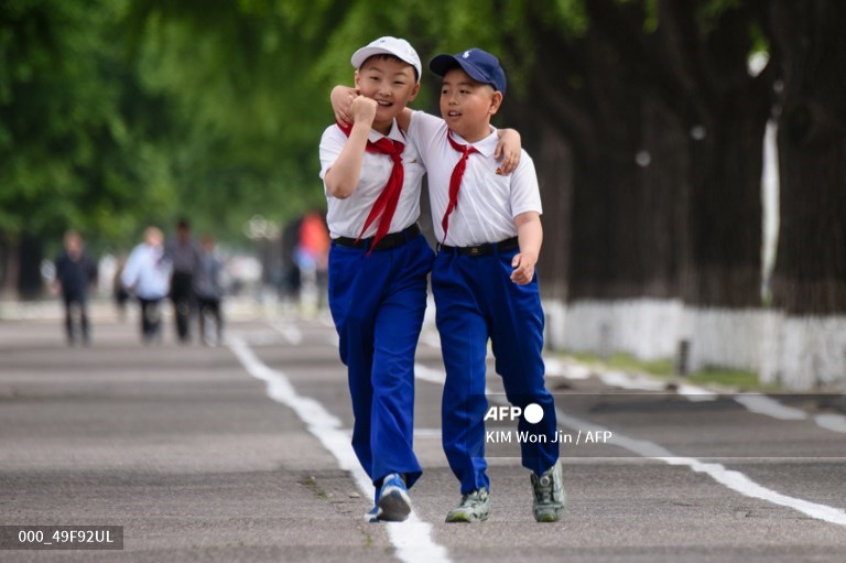 Deux enfants, membres du KCU, marchent dans une rue de Pyongyang