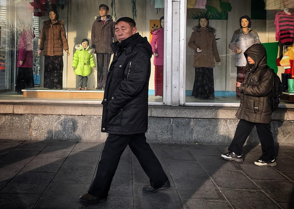 Un homme marche devant la vitrine d'un grand magasin de Pyongyang