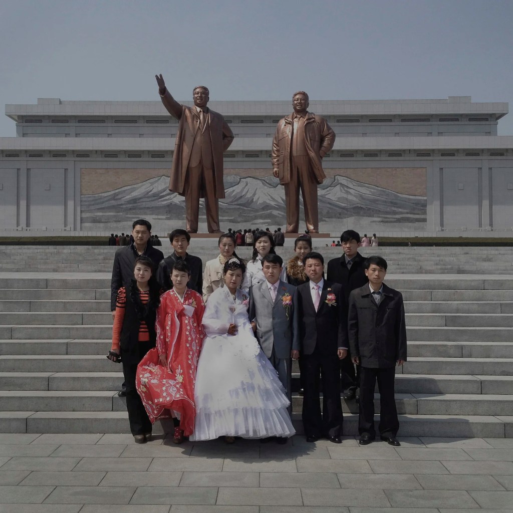 Un groupe se fait prendre en photo devant un monument de Corée du Nord