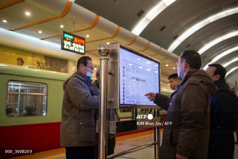 des personnes lisent le journal à disposition dans la station de métro