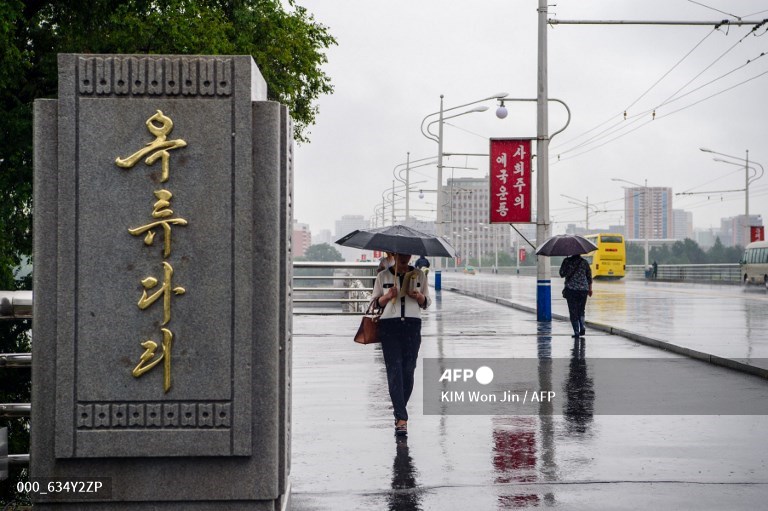 Des personnes marchent sur un pont, abritées par un parapluie