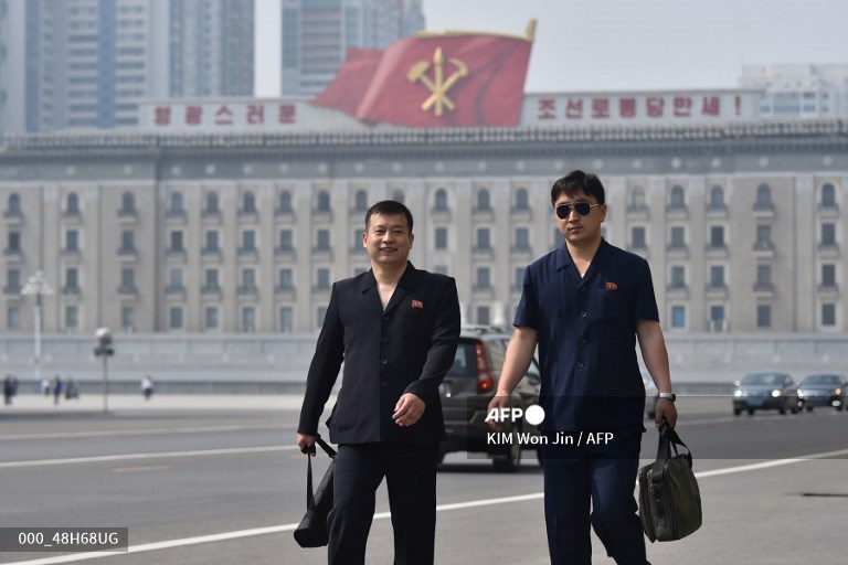 deux hommes marchent dans une ru de Pyongyang