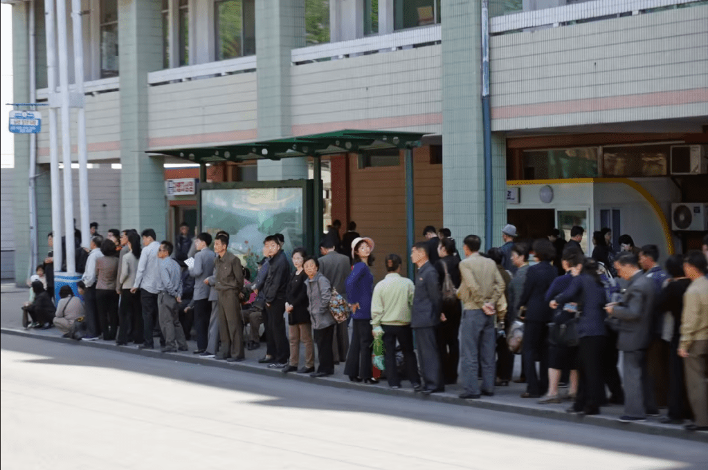 Des Nord-Coréens font la queue à un arrêt de bus à Pyongyang